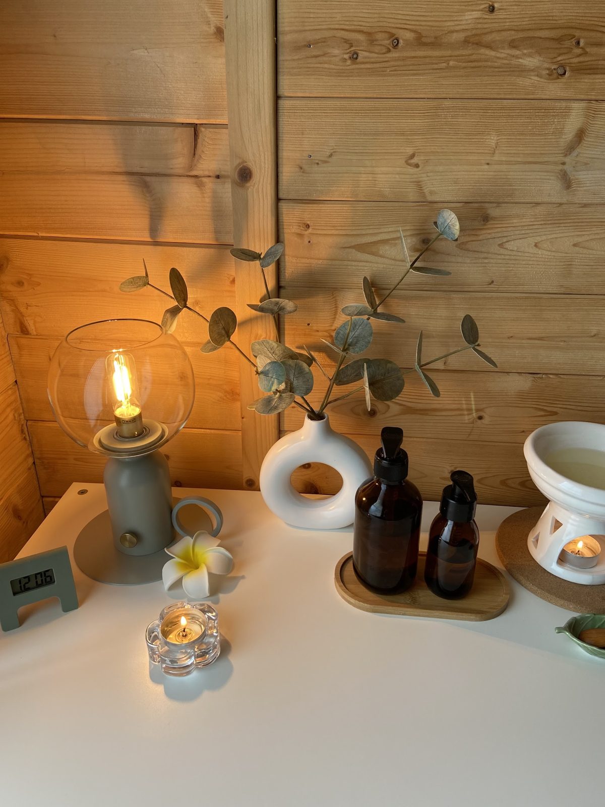 A candle lantern, eucalyptus and bottles of massage oil on the side table in our studio