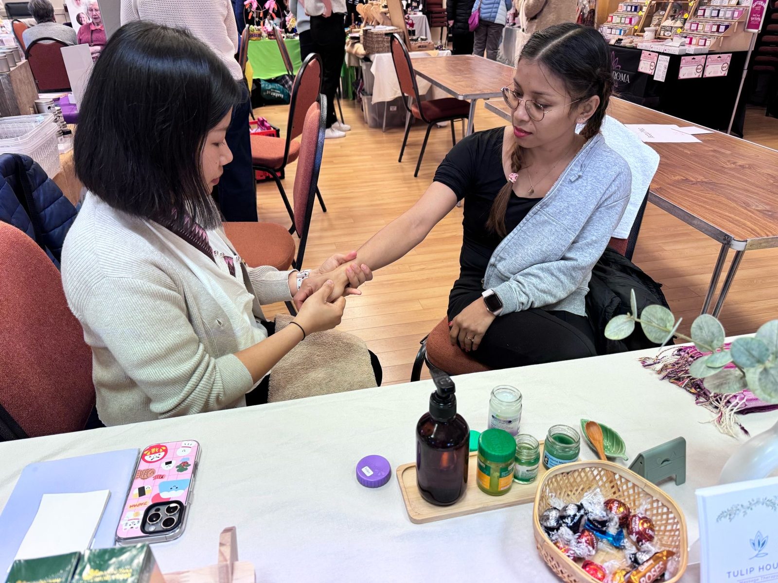Our therapist giving a hand treatment at a Tulip House stall at an indoor fair
