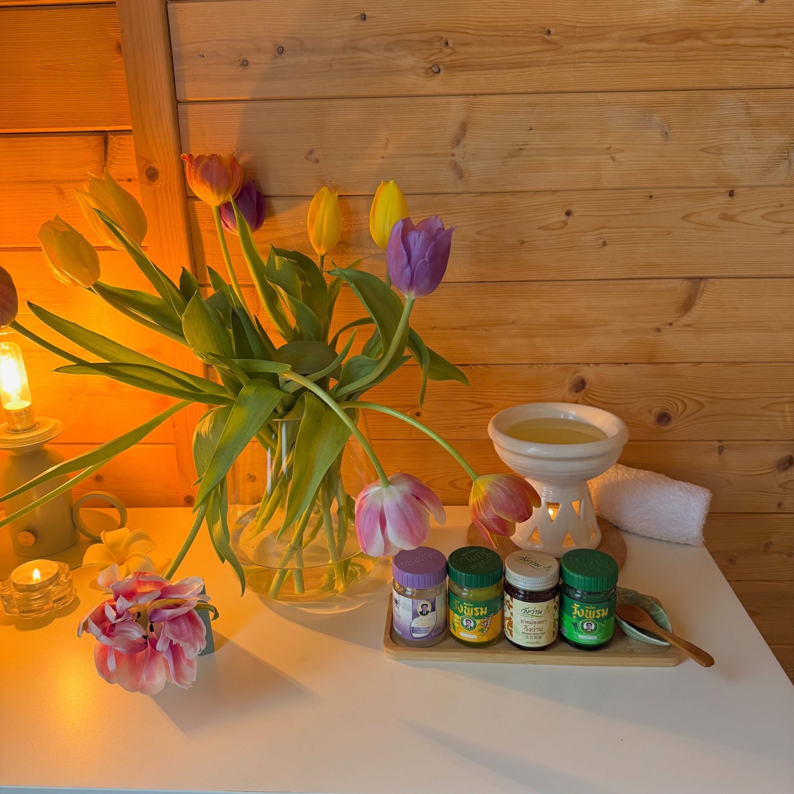 Tulips, candles, an oil burner and jars of herbal balm on the studio side table